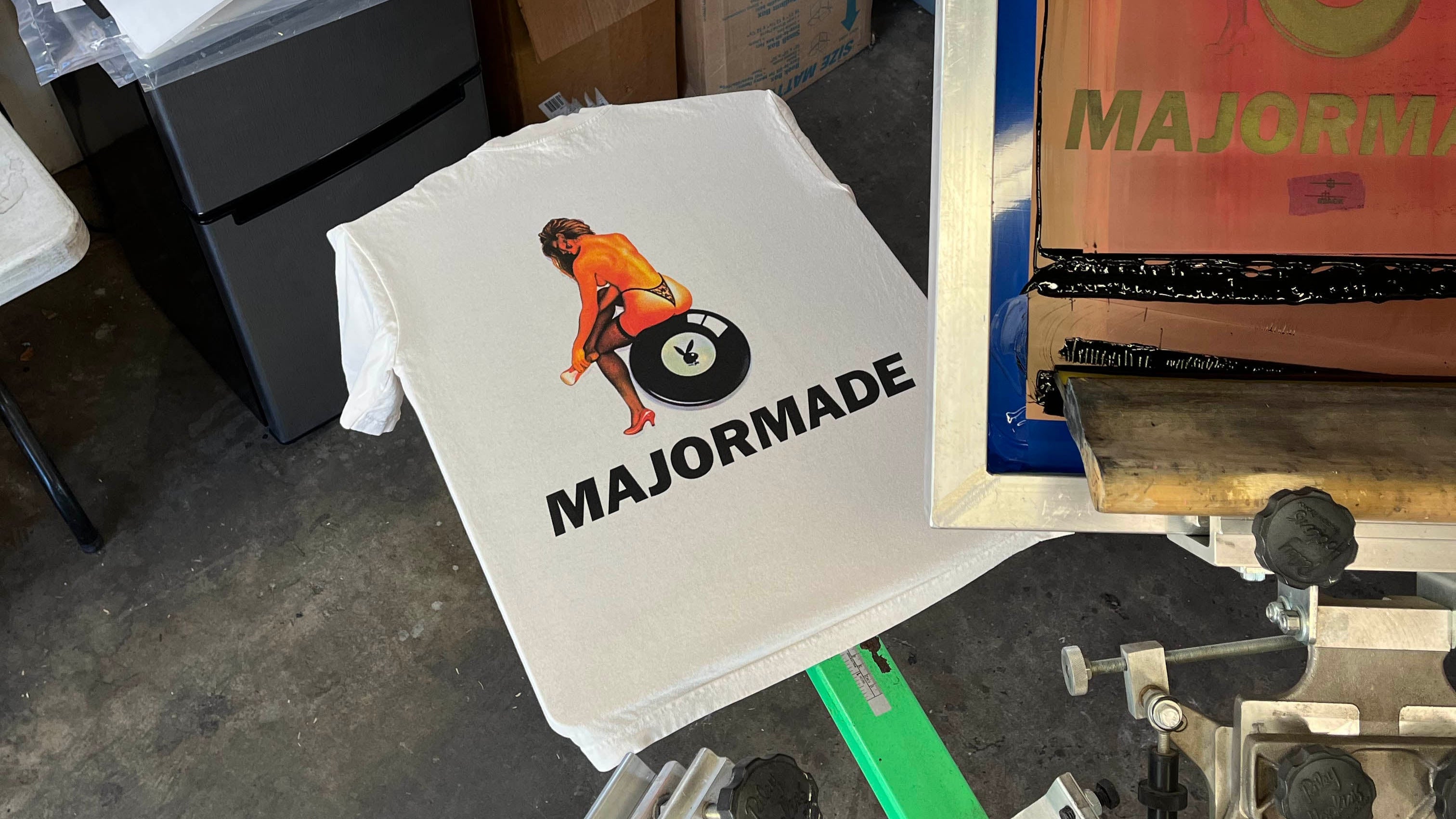 T-shirts with 'MAJORMADE' design on a screen printing press.