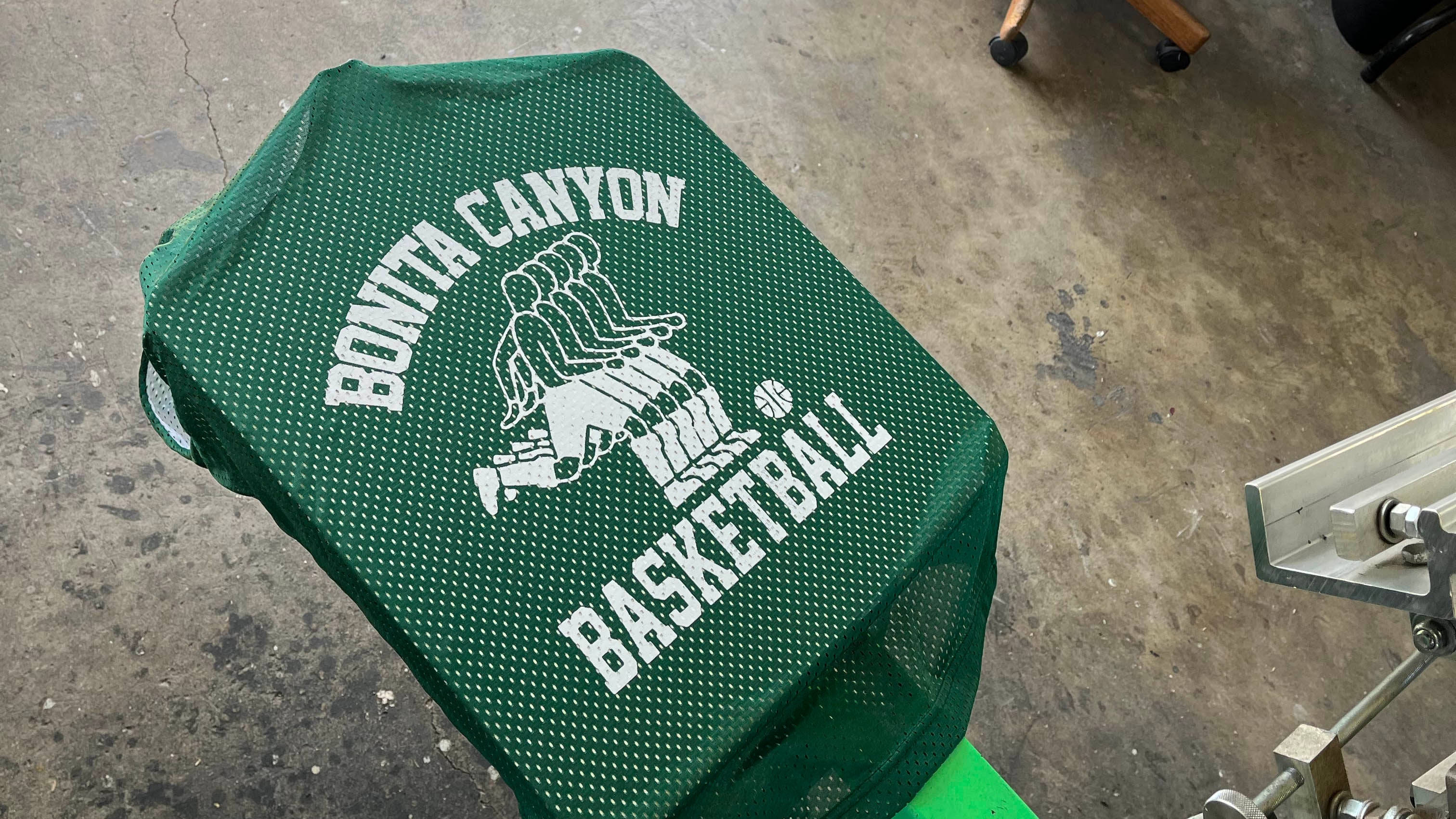 Green basketball chair with 'Bonta Canyon Basketball' logo on a concrete floor.